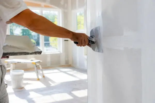 Drywall finisher smoothing joint compound on a new wall