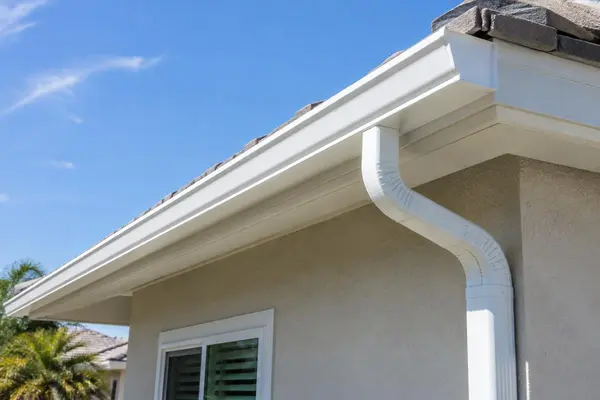 Seamless white gutter and downspout on a stucco home