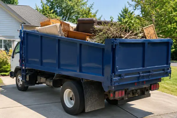 Junk removal truck loaded with old furniture and yard debris