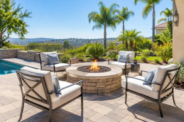 Paver patio with a stone fire pit and lounge chairs in a hillside backyard