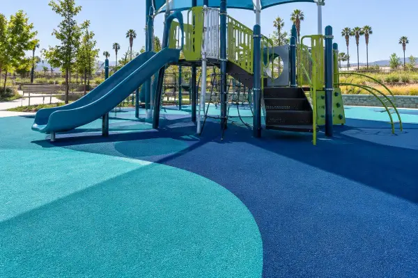 Teal and navy poured in place rubber surfacing under a park playground